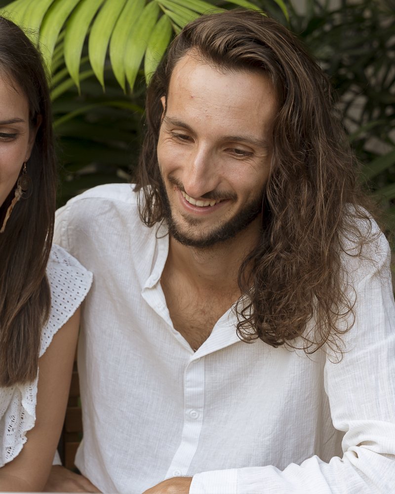 Jonathan sourit, assis devant l'ordinateur portable dans un jardin tropical